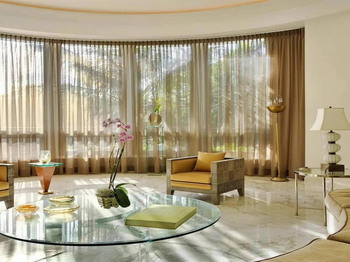 Sala com cortinas de voil do piso ao teto acompanhando a parede curva.