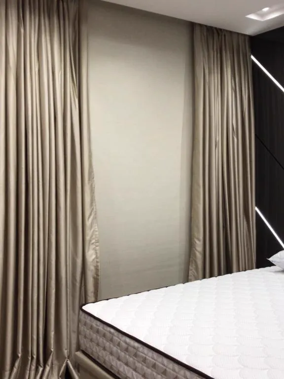 Quarto com rolo blackout na janela e xale reto em shantung ao lado da cama.