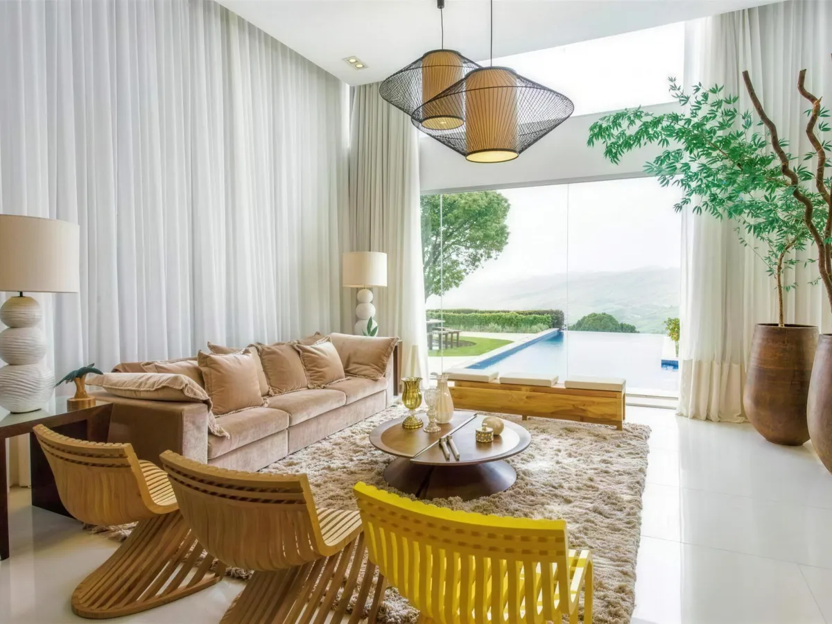 Sala ampla com cortinas brancas e vista para a piscina.
