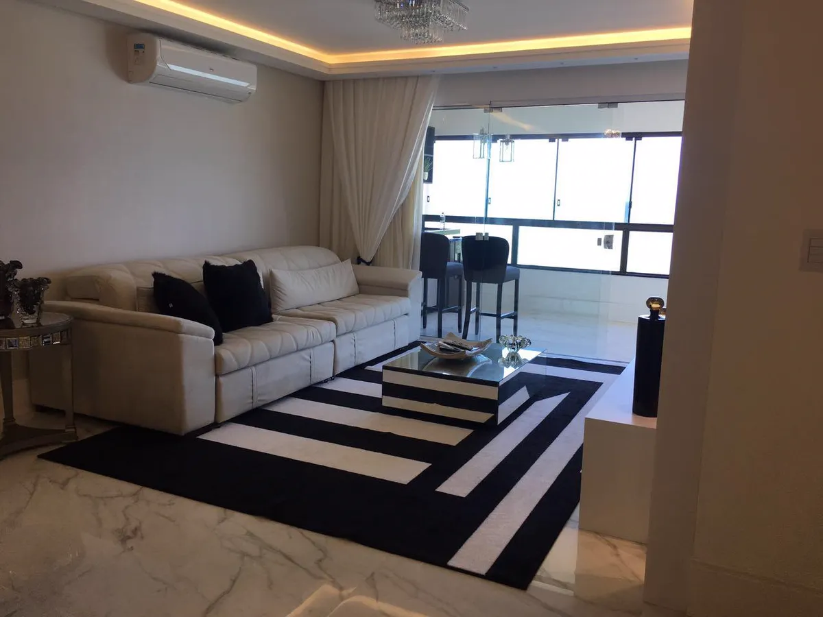 Sala de estar com sofá claro e tapete listrado em preto e branco.