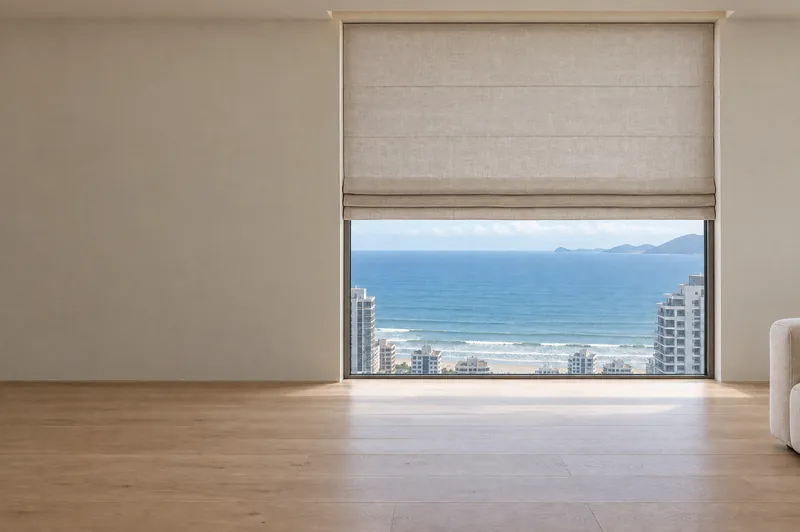 A mesma janela para o mar com cortina romana recolhida em dobras no alto.