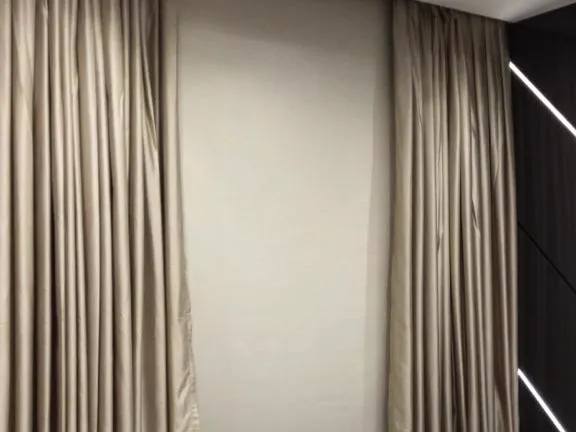 Quarto com rolo blackout na janela entre xales retos de shantung, ao lado da cama.
