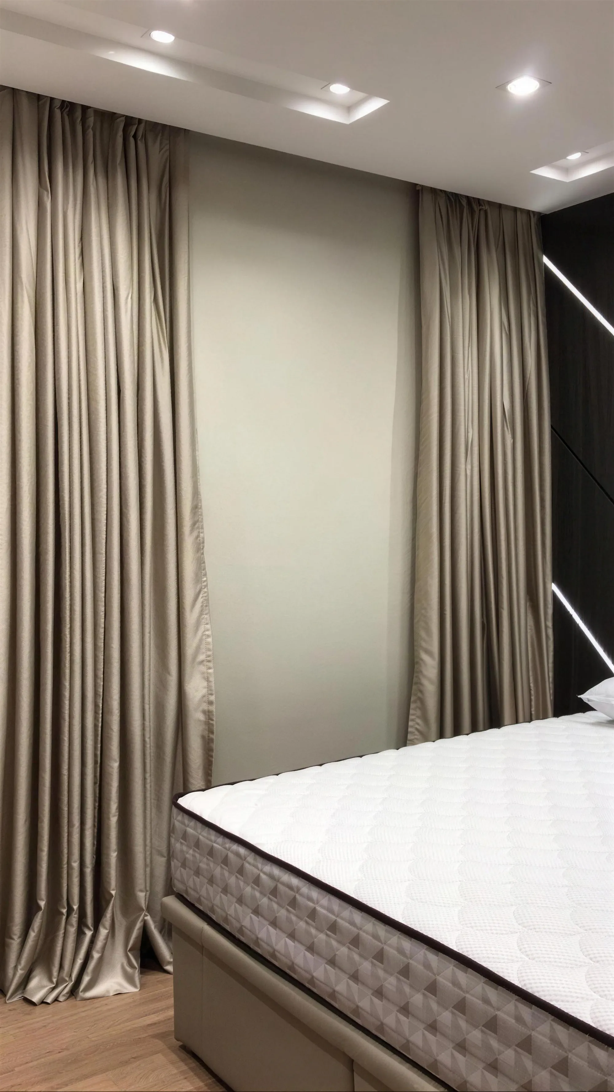 Quarto com rolo blackout na janela entre xales retos de shantung, ao lado da cama.