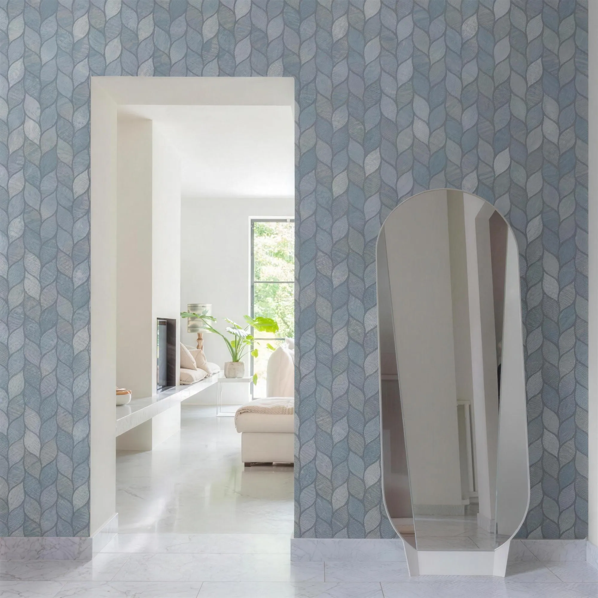 Parede com papel de parede de pétalas em azul-acinzentado, passagem para uma sala clara e espelho apoiado no chão.