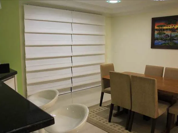 Sala de jantar com cortina Cascade branca em ondulações horizontais na janela.