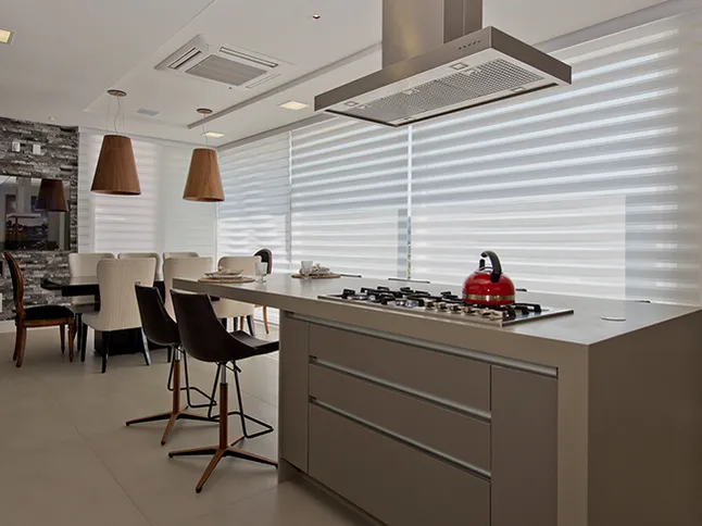 Cozinha com ilha e persianas Double Vision brancas nas janelas, com a mesa de jantar ao fundo.