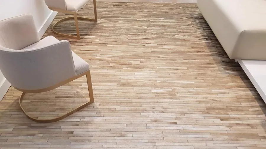 Tapete de couro em tiras de tons bege, com poltronas claras de base dourada.