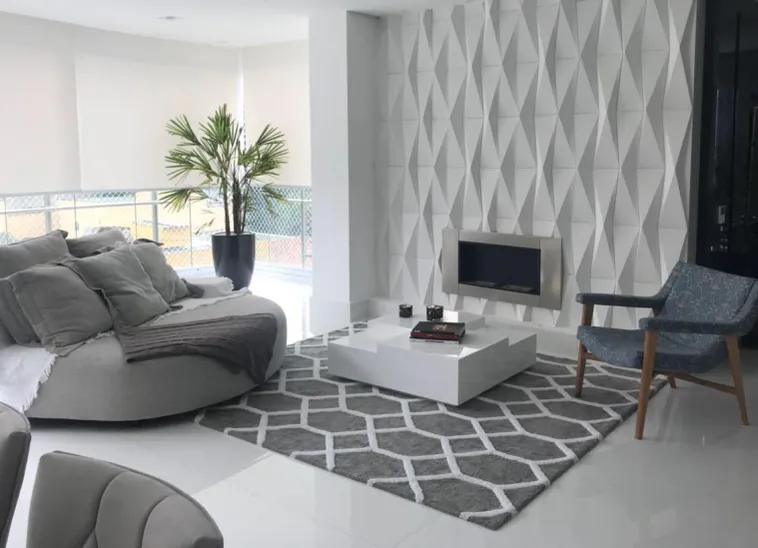 Sala branca com parede em relevo, lareira e tapete cinza com desenho geométrico branco.